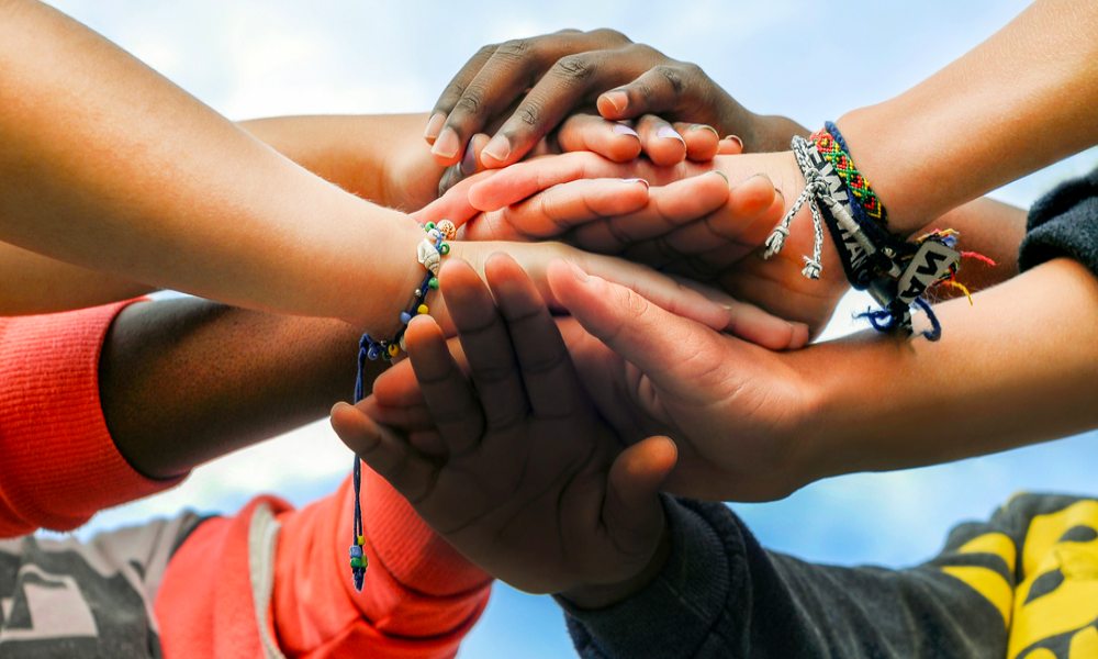 A powerful image of diverse, multiracial hands stacked together in unity and support against GBV. Showing the collective efforts and solidarity during the 16 Days of Activism campaign against Gender-Based Violence (GBV) in South Africa.