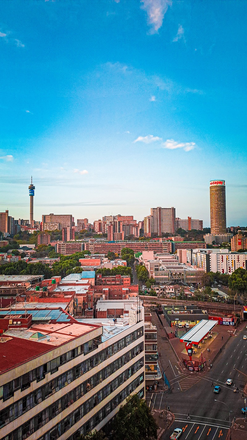 A panoramic view of Johannesburg cityscape showcasing modern buildings against a clear blue sky. Showing a safe, clean city with impeccable road safety and South Africa's improved border control and efforts against xenophobia.